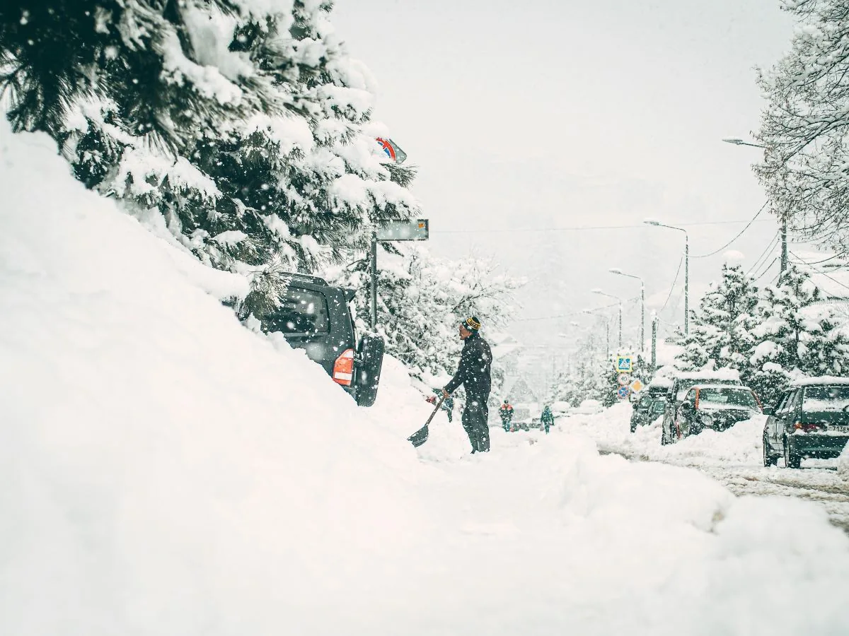Snowfall and strong winds reduce visibility on a mountain highway in the Rockies
